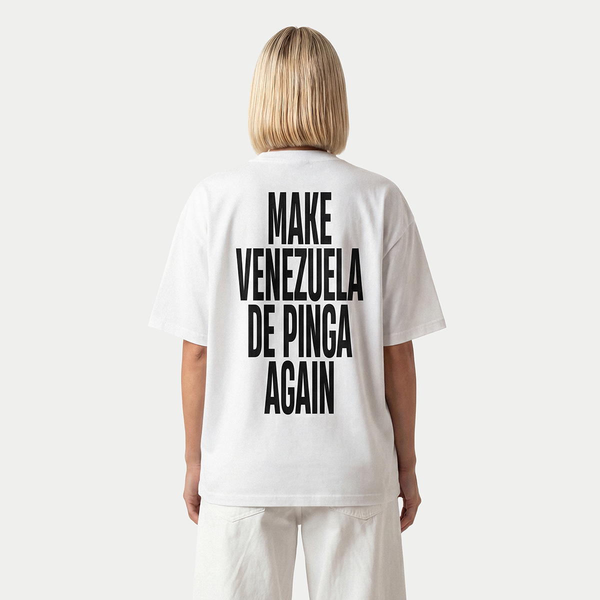 Modelo de espaldas llevando la camiseta blanca «Make Venezuela De Pinga Again» de Caracas Merch